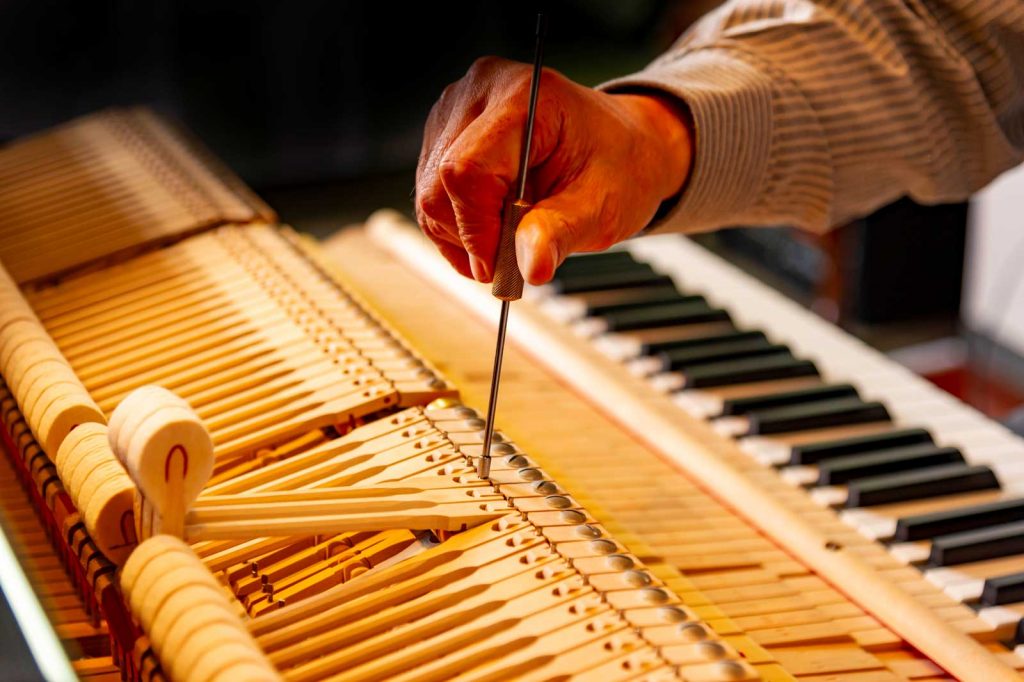 Klavierstimmer stimmt ein Klavier mit Werkzeug.